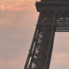Tour Eiffel vue en contre-plongée au coucher du soleil, ciel aux teintes orangées et roses