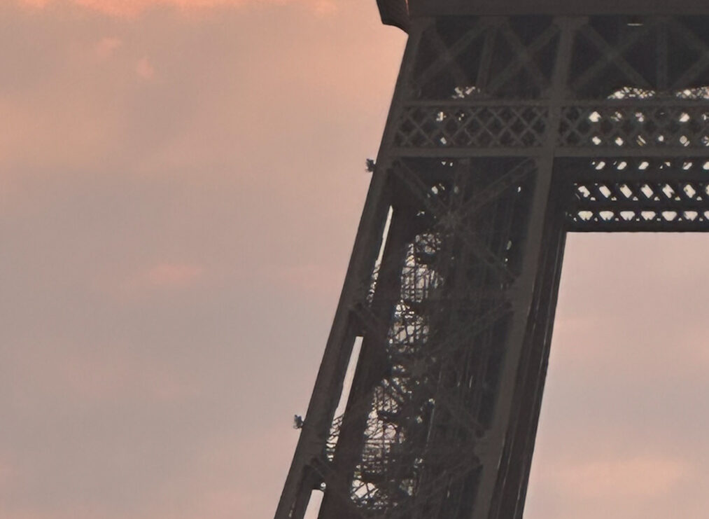 Tour Eiffel vue en contre-plongée au coucher du soleil, ciel aux teintes orangées et roses