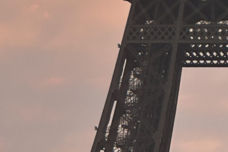 Tour Eiffel vue en contre-plongée au coucher du soleil, ciel aux teintes orangées et roses