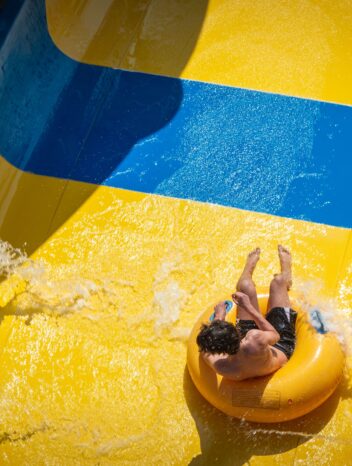 Vue aérienne d'une personne dévalant un toboggan aquatique jaune et bleu sur une bouée