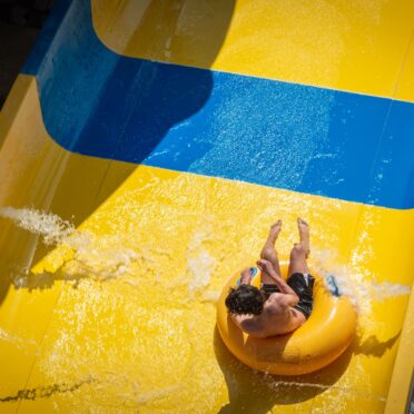 Vue aérienne d'une personne dévalant un toboggan aquatique jaune et bleu sur une bouée