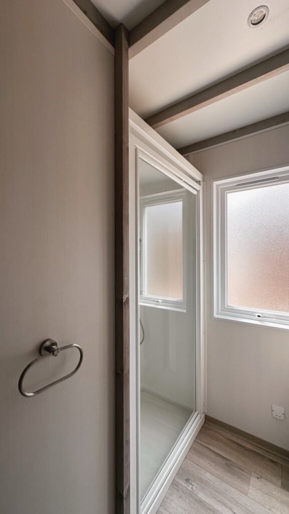 Salle de bain avec cabine de douche vitrée, porte-serviette anneau et fenêtre à vitrage dépoli