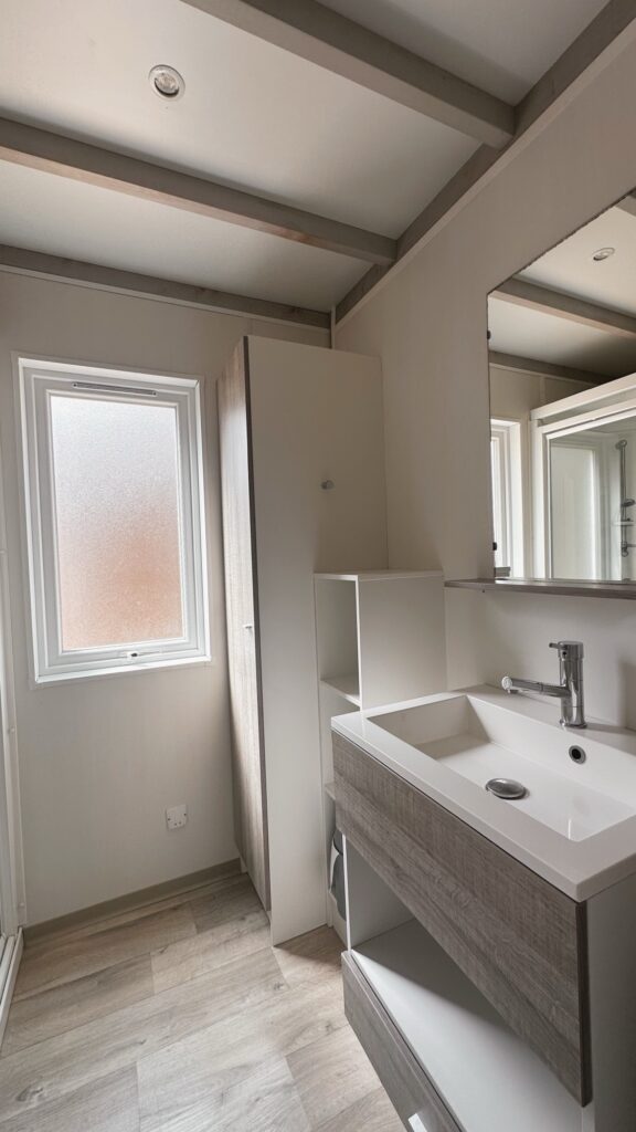 Salle de bain avec vasque, miroir, rangements muraux et fenêtre à vitrage dépoli